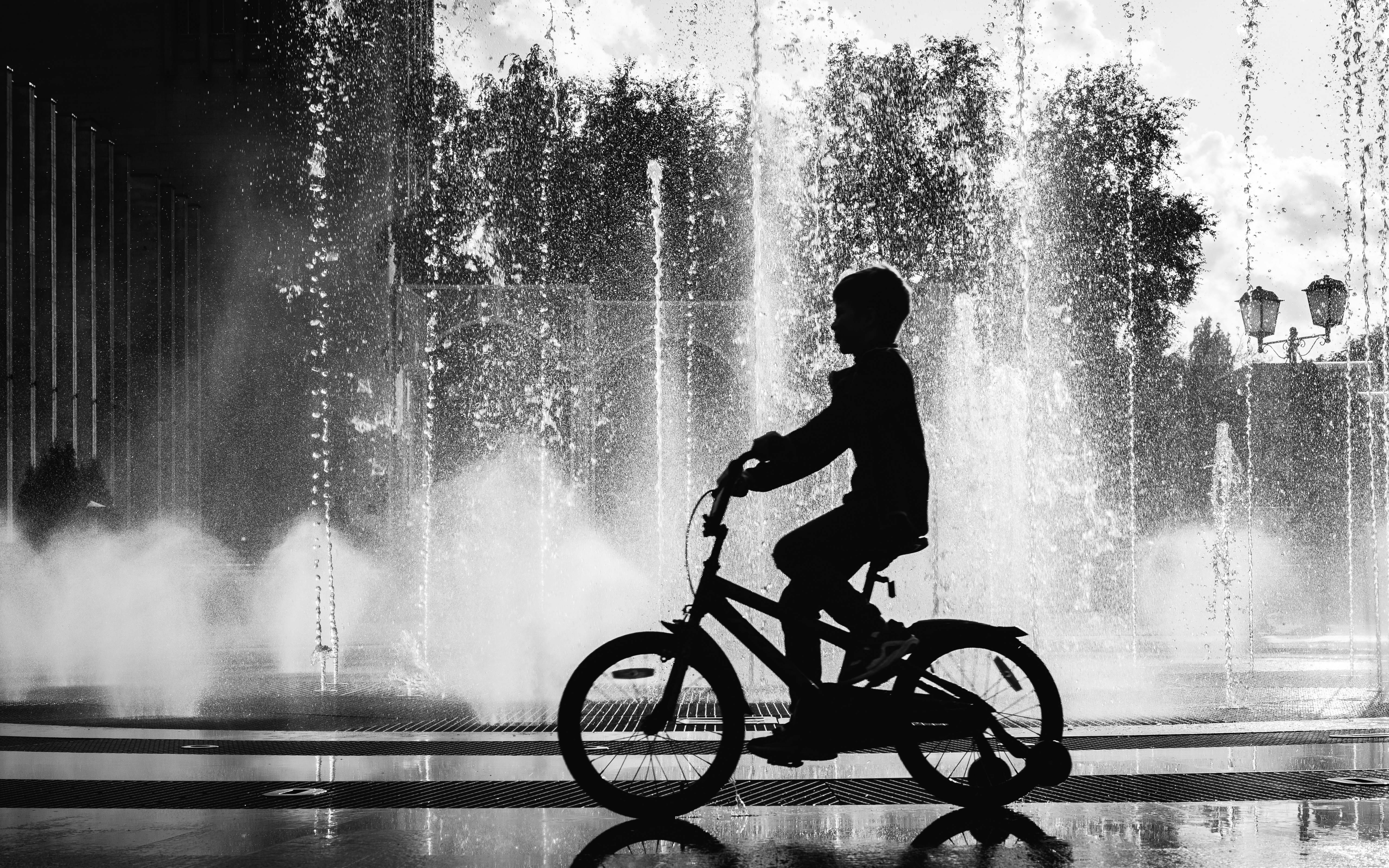 Kid Cycling Near a Fountain